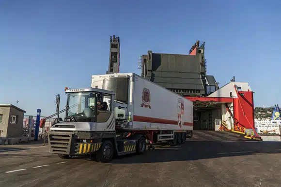 Camion poids lourd sortant d'un bateau et roulant sur le quai